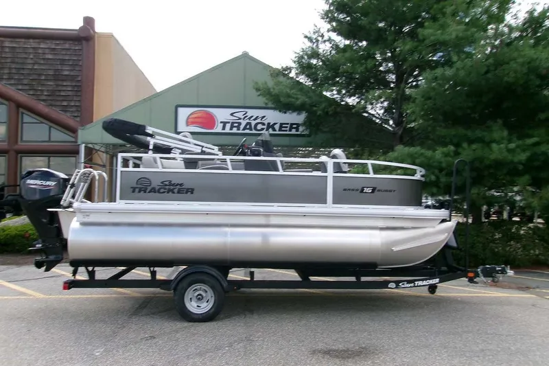 The Image of 2026 Sun Tracker Bass Buggy 16 XL Select pontoon boat on trailer, parked outdoors. - 0