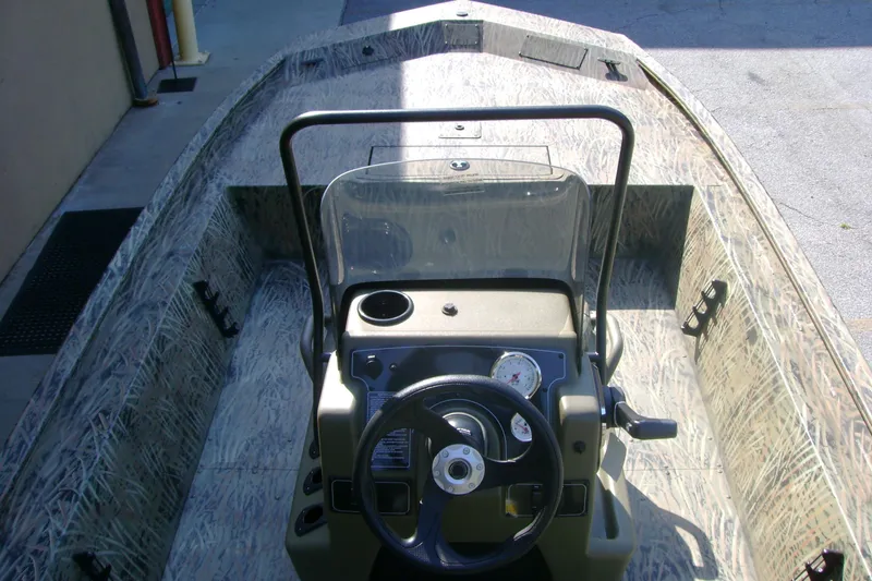 Slide: The Image of 2026 Tracker Grizzly 1860 CC boat interior with steering console and camouflage design. - 5
