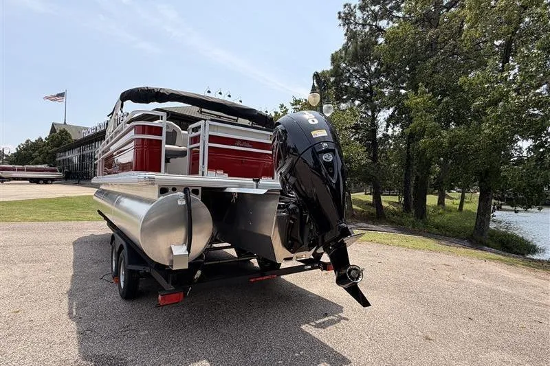 Slide: The Image of 2026 Sun Tracker Fishin' Barge 22 XP3 pontoon boat on trailer, parked near trees. - 4