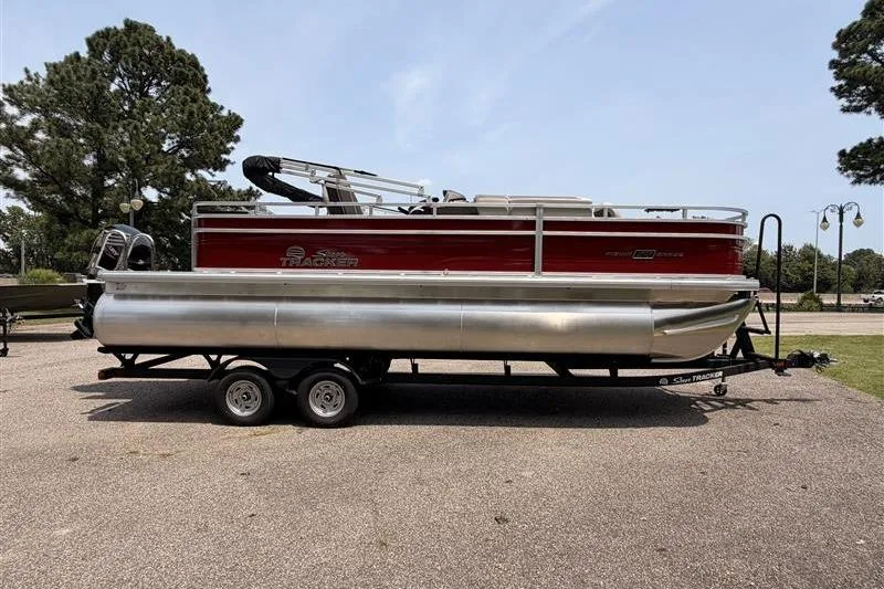 Slide: The Image of 2026 Sun Tracker Fishin' Barge 22 XP3 pontoon boat on trailer, parked outdoors. - 5