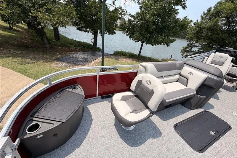 Slide: The Image of 2026 Sun Tracker Fishin' Barge 22 XP3 interior with seating, near a scenic lakeside. - 9