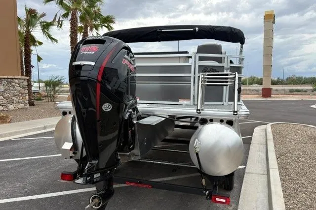 Slide: The Image of 2026 Sun Tracker Fishin' Barge 20 DLX pontoon boat with powerful outboard motor in parking lot. - 1