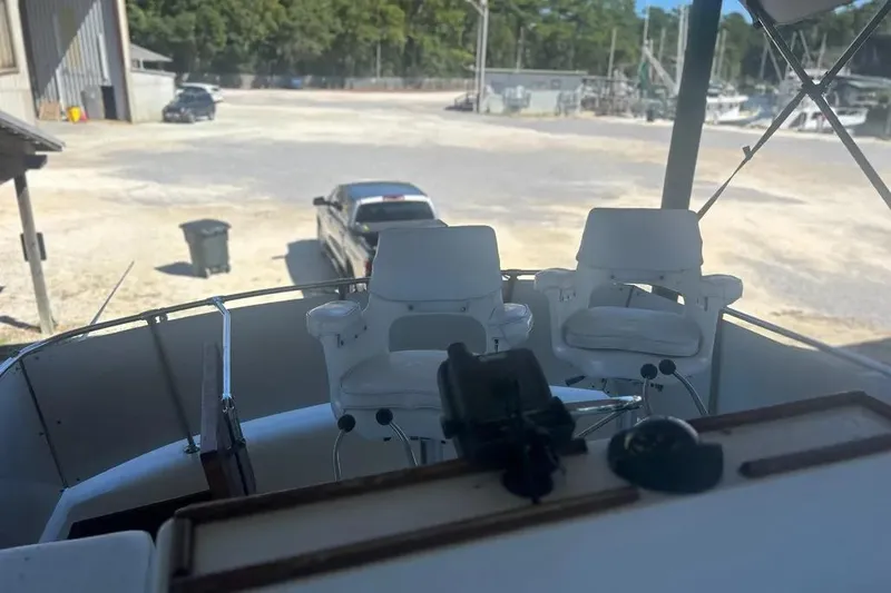 Slide: The Image of 1978 Chris-Craft 45 Commander boat helm with white captain chairs, parked in a marina. - 12