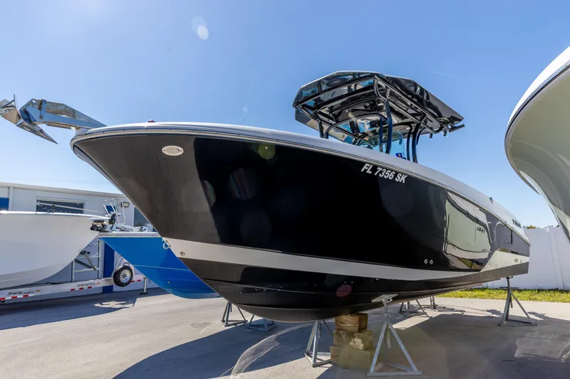 Slide: The Image of 2019 Wellcraft 262 Fisherman boat on stands, black hull, sunny day. - 4
