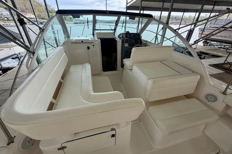 Slide: The Image of 2000 Tiara Yachts 2900 Coronet interior with white seating and helm, docked by water. - 24