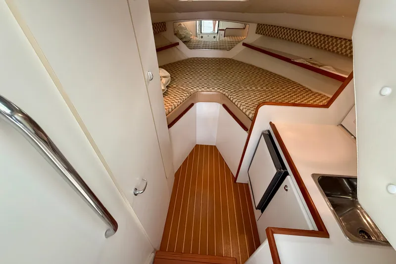 Slide: The Image of Interior of 2000 Tiara Yachts 2900 Coronet, featuring cabin with bed, kitchenette, and wood flooring. - 48