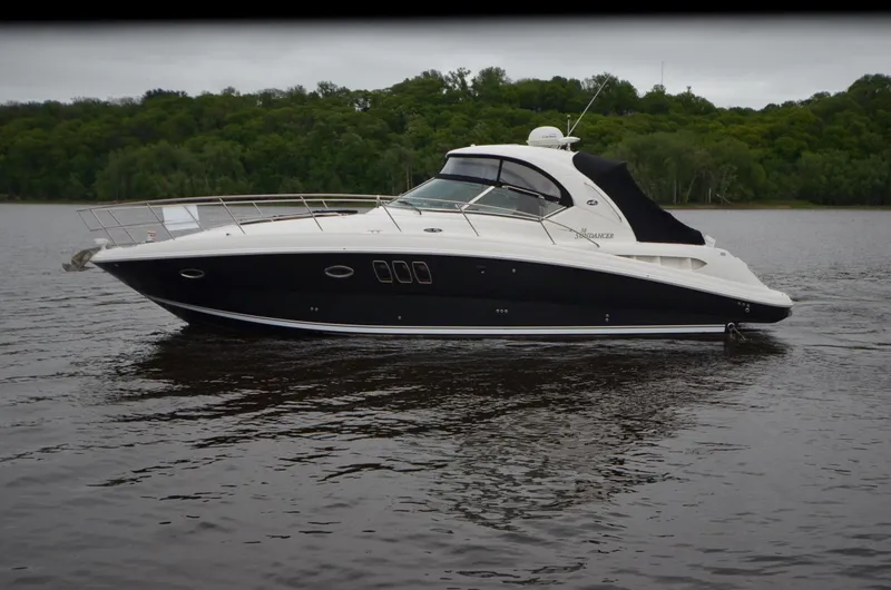 Slide: The Image of 2007 Sea Ray 38 Sundancer yacht on a serene lake with lush green forest backdrop. - 41