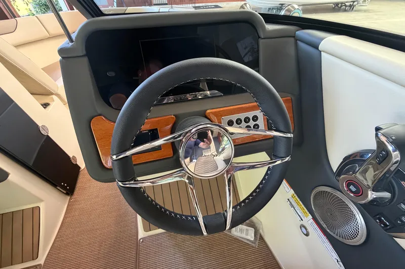 Slide: The Image of 2027 Chris-Craft Sportster 25 dashboard with steering wheel, wood accents, and modern controls. - 36