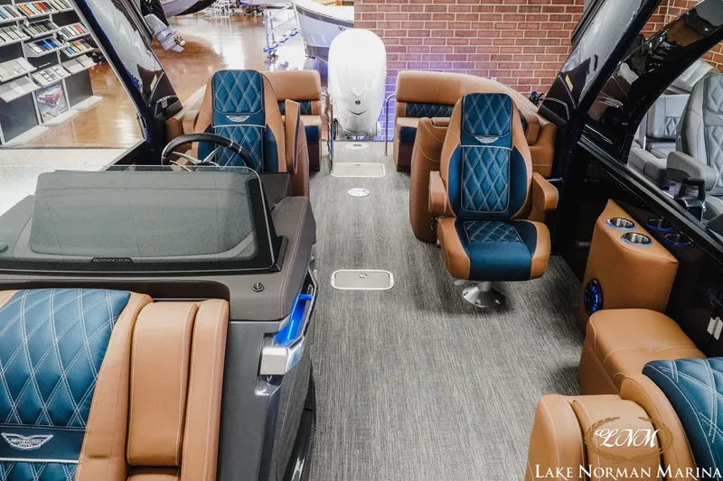 Slide: The Image of 2026 Bennington 25QXFBA luxury boat interior with blue and brown seating at Lake Norman Marina. - 12