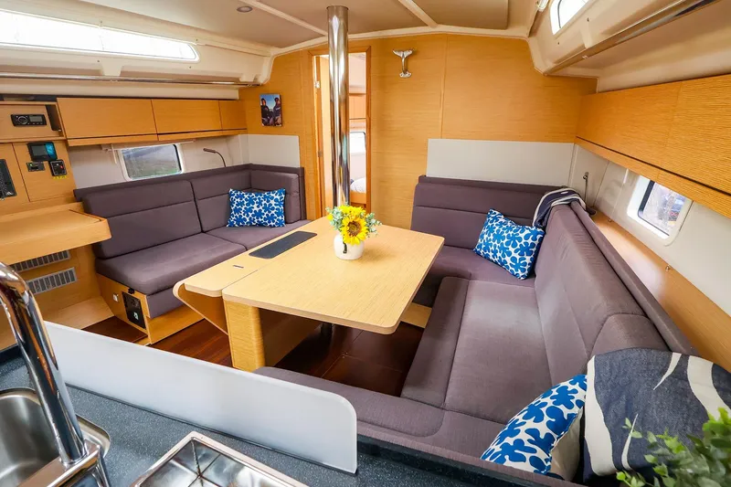 Slide: The Image of 2019 Hanse 418 yacht interior with cozy seating, wooden table, and decorative cushions. - 23