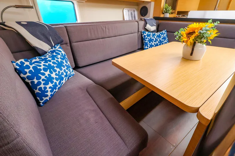 Slide: The Image of Interior of 2019 Hanse 418 yacht with cozy seating, floral cushions, and a wooden table. - 29