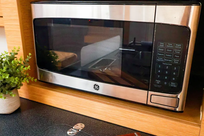Slide: The Image of Stainless steel GE microwave in a modern kitchen setting with wooden cabinetry. - 34