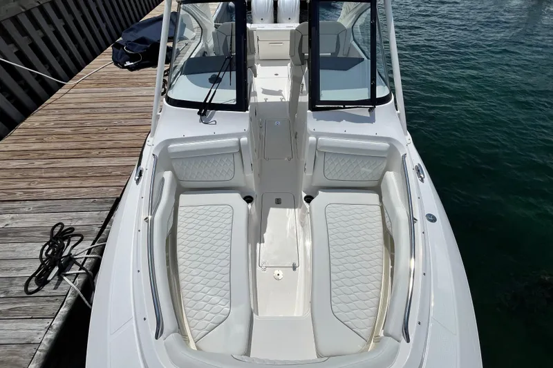 Slide: The Image of 2027 Pursuit DC 326 Dual Console boat with white seating, docked by wooden pier. - 18
