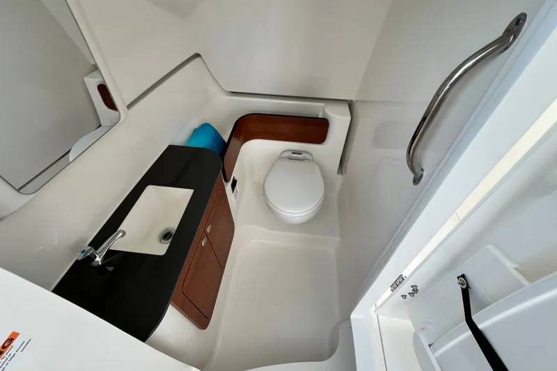 Slide: The Image of 2027 Pursuit DC 326 Dual Console boat bathroom with sink, toilet, and handrail. - 14