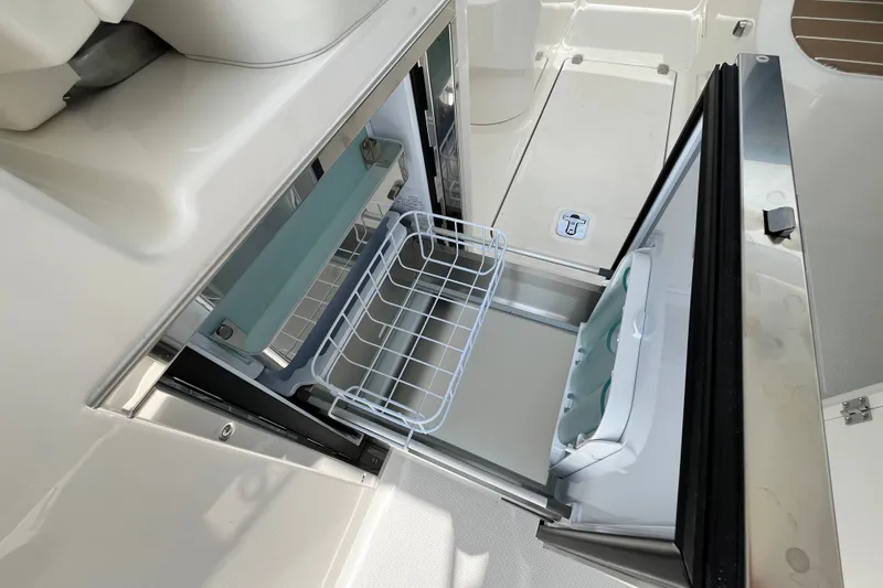 Slide: The Image of Open storage compartment on 2027 Pursuit DC 326 Dual Console boat, featuring a wire basket. - 5