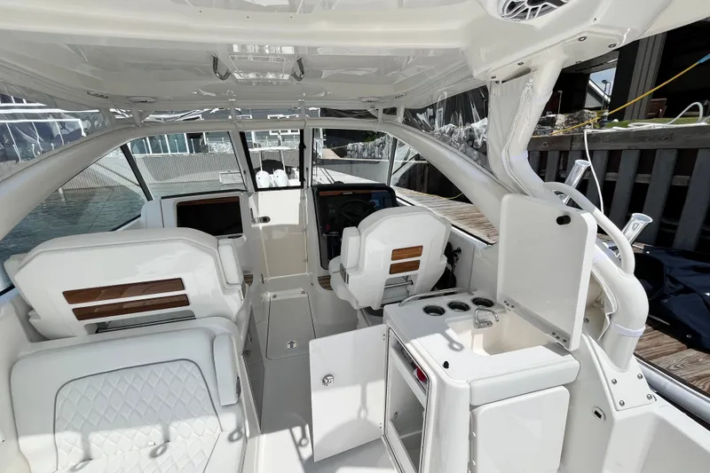 Slide: The Image of 2027 Pursuit DC 326 Dual Console boat interior with white seating and helm station. - 7