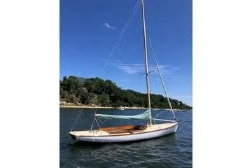 Slide: The Image of 1997 Stuart Marine Knockabout sailboat on calm water near a wooded shoreline. - 2