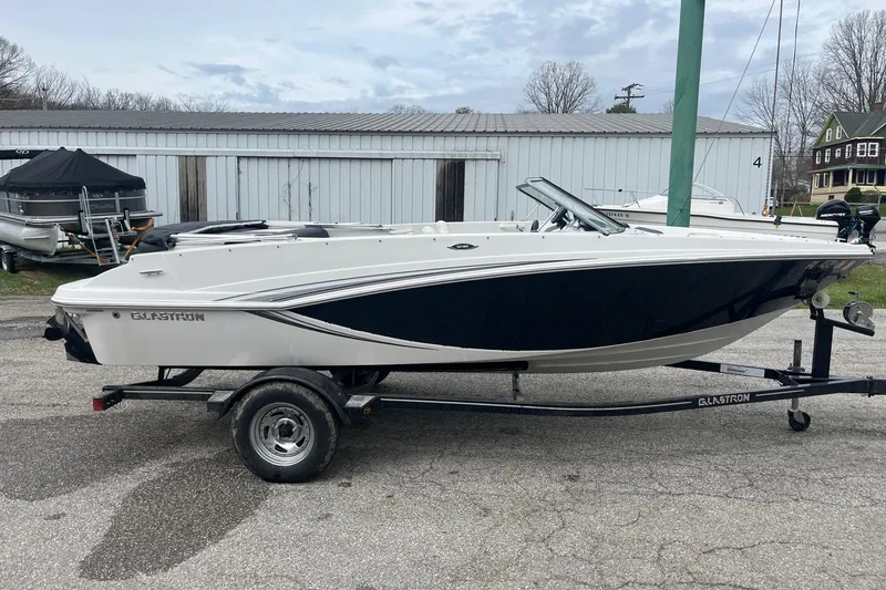 Slide: The Image of 2014 Glastron GT 185 boat on trailer, parked outdoors near storage buildings. - 4