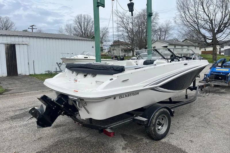 Slide: The Image of 2014 Glastron GT 185 boat on trailer, parked outdoors near a garage. - 5