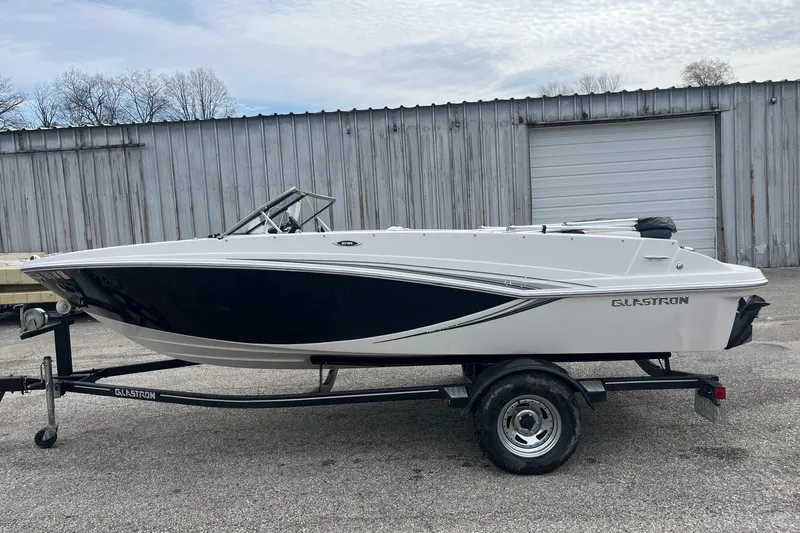 Slide: The Image of 2014 Glastron GT 185 boat on trailer, parked outside a metal building. - 7