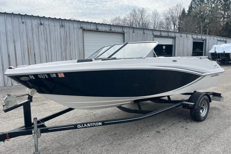 Slide: The Image of 2014 Glastron GT 185 boat on trailer, parked outside a metal building. - 8
