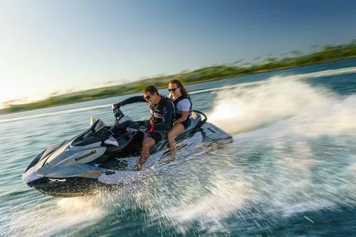 Slide: The Image of 2026 Kawasaki Jet Ski STX speeding on water with two riders enjoying the ride. - 3