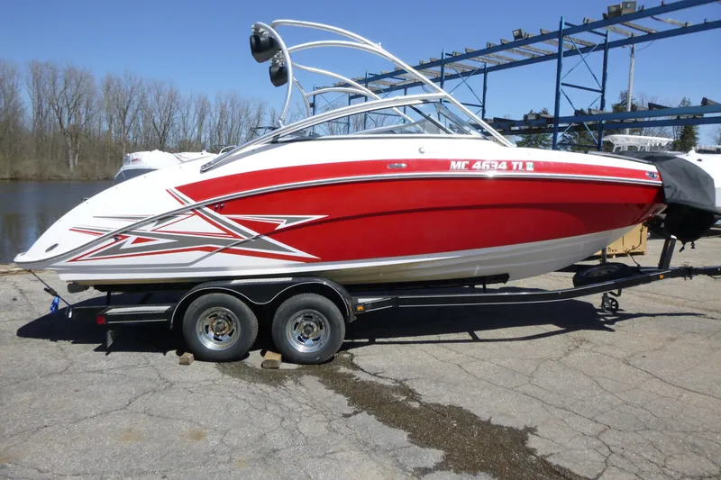 The Image of 2011 Yamaha Boats AR240 HO in red and white on a trailer by the water. - 1