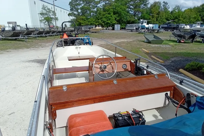 Slide: The Image of 1985 Boston Whaler 13 Sport boat with wooden dashboard and steering wheel in a boatyard. - 11