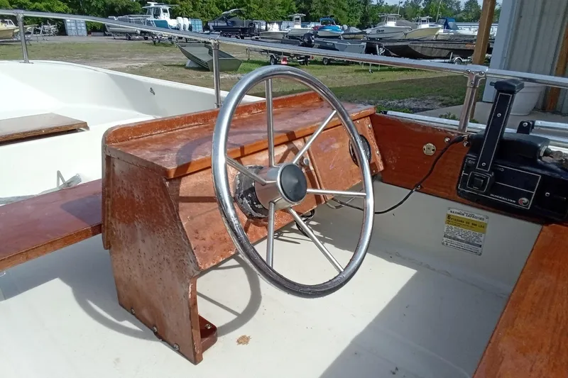 Slide: The Image of 1985 Boston Whaler 13 Sport boat steering console with wooden finish and metal wheel. - 13