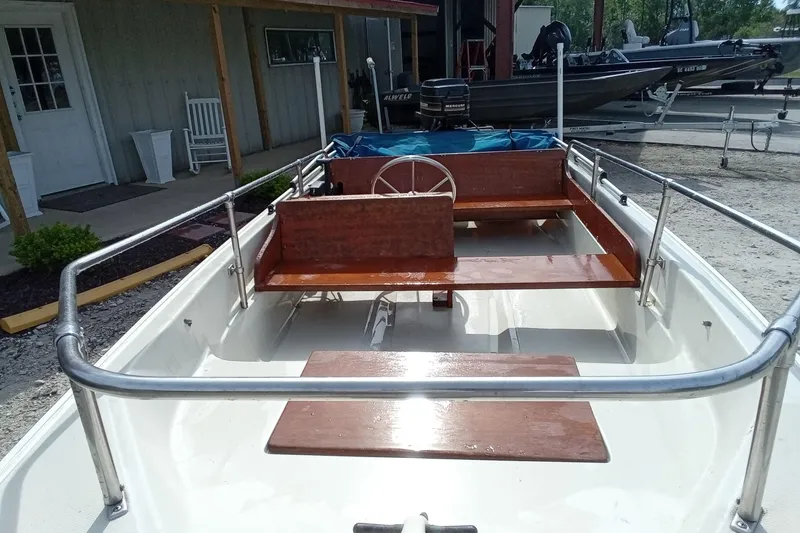 Slide: The Image of 1985 Boston Whaler 13 Sport boat with wooden seating and steering wheel, parked outdoors. - 4