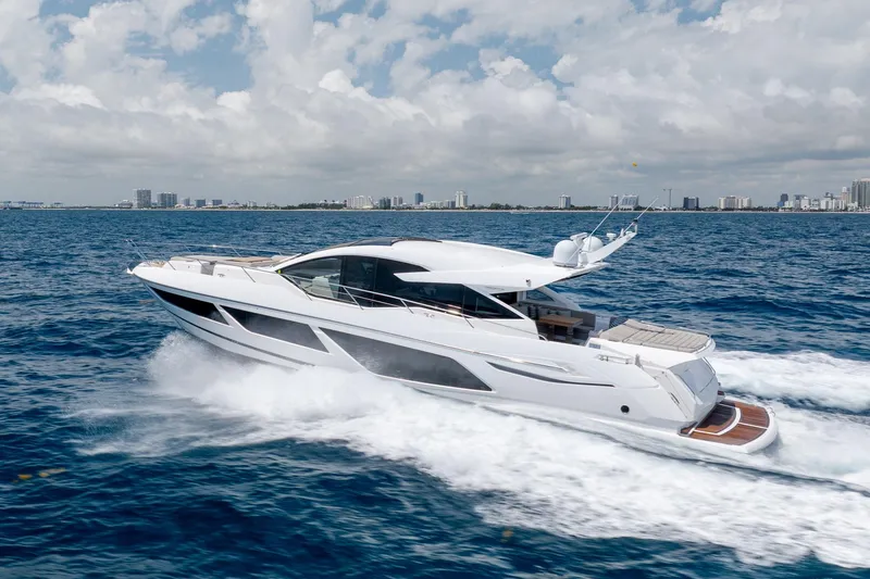 Slide: The Image of 2020 Sunseeker Predator 74 XPS yacht cruising on open water with city skyline backdrop. - 110
