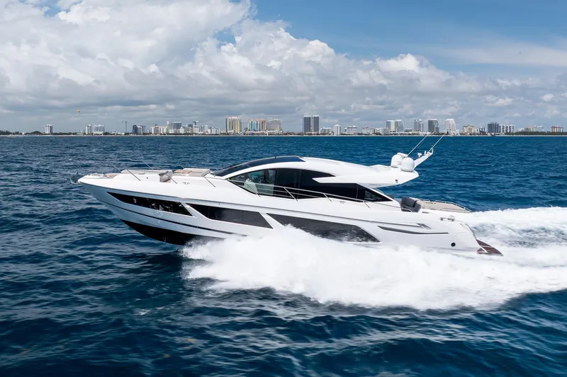 Slide: The Image of 2020 Sunseeker Predator 74 XPS yacht cruising on ocean with city skyline backdrop. - 113