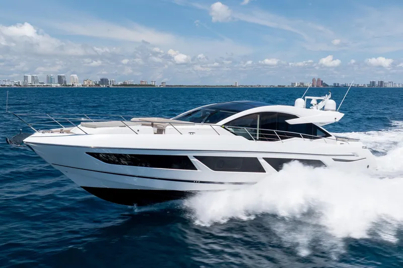 Slide: The Image of 2020 Sunseeker Predator 74 XPS yacht cruising on open water, city skyline in background. - 114