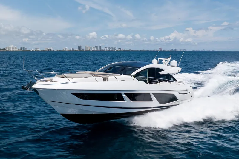 Slide: The Image of 2020 Sunseeker Predator 74 XPS yacht cruising on open sea with city skyline. - 122