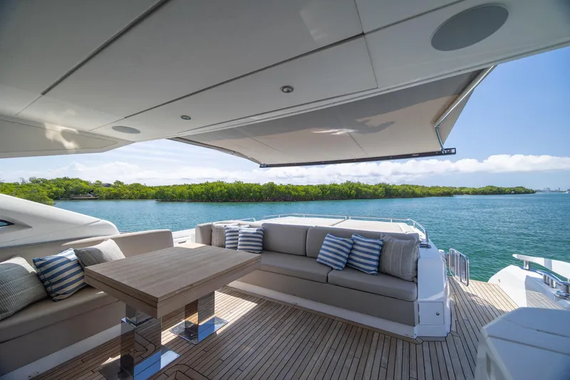Slide: The Image of Luxurious Sunseeker Predator 74 XPS yacht deck with seating, table, and scenic ocean view. - 76