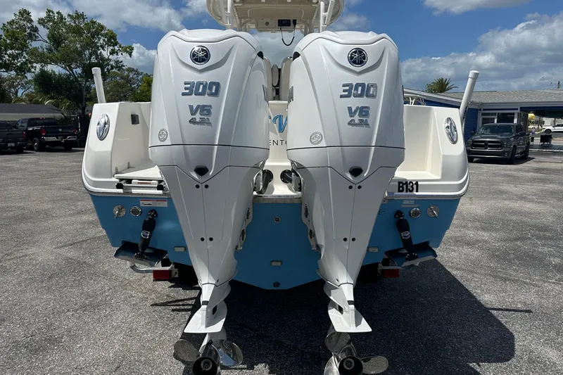 Slide: The Image of Twin Yamaha 300 V6 engines on a 2022 Sailfish 290 CC boat, parked outdoors. - 2