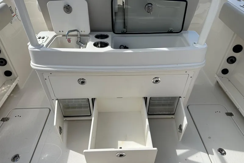 Slide: The Image of 2022 Sailfish 290 CC boat interior with sink, storage compartments, and cup holders. - 30