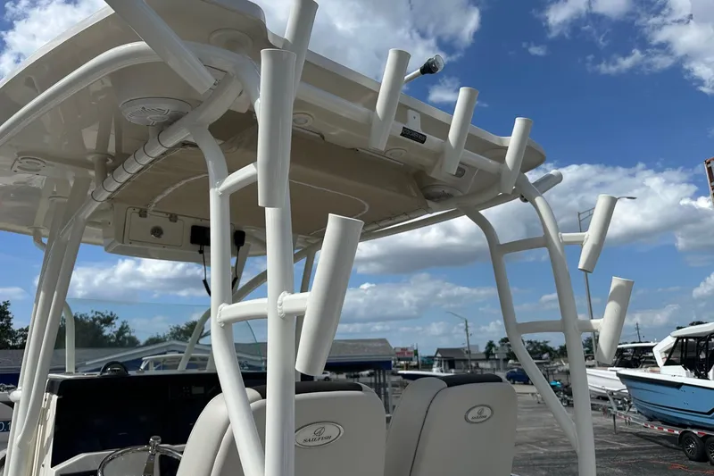 Slide: The Image of 2022 Sailfish 290 CC boat with rod holders and T-top under a blue sky. - 36