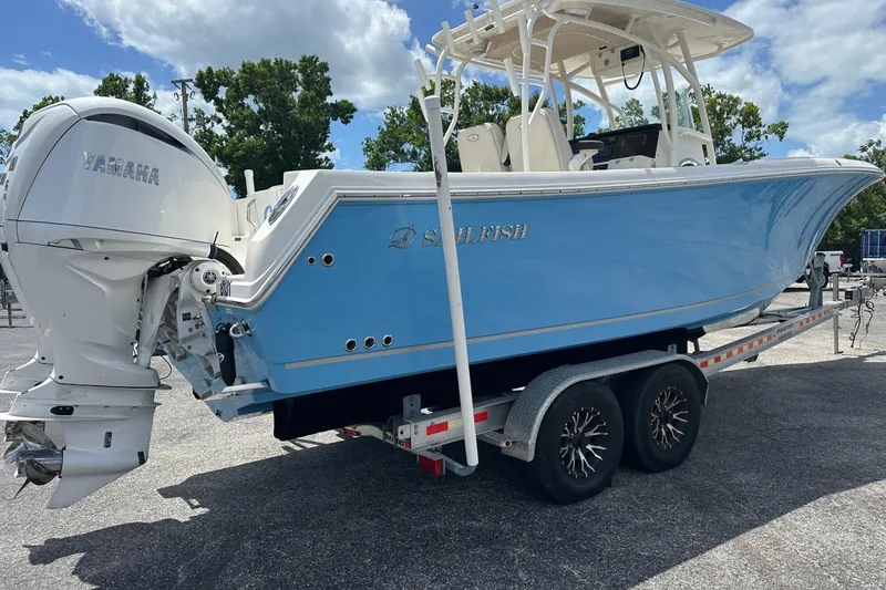 Slide: The Image of 2022 Sailfish 290 CC boat on trailer with Yamaha engine, under a partly cloudy sky. - 5