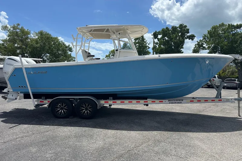 Slide: The Image of 2022 Sailfish 290 CC boat on trailer, blue hull, parked outdoors under clear sky. - 6