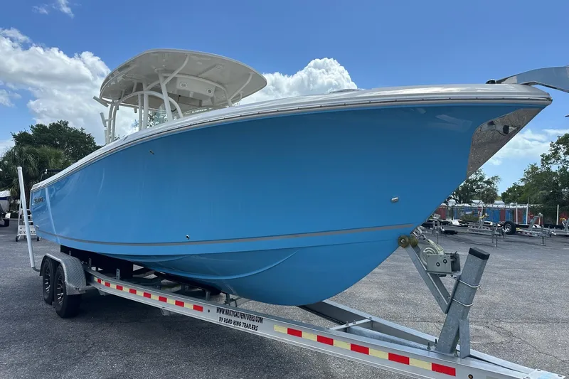 Slide: The Image of 2022 Sailfish 290 CC boat on trailer, blue hull, clear sky background. - 8