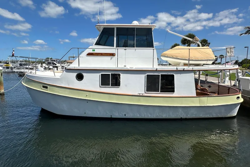Slide: The Image of 1987 Kadey-Krogen Manatee 36 yacht docked in a sunny marina, featuring classic design. - 2