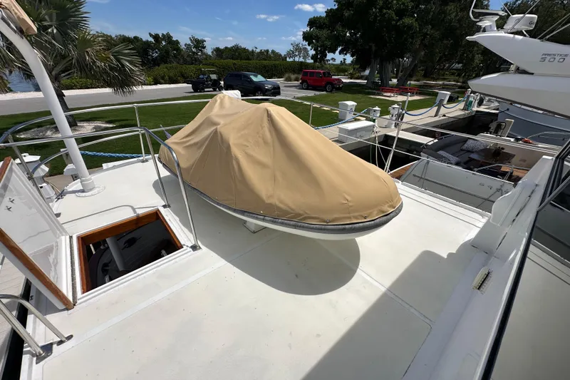 Slide: The Image of 1987 Kadey-Krogen Manatee 36 yacht deck with covered equipment, docked near lush greenery. - 85