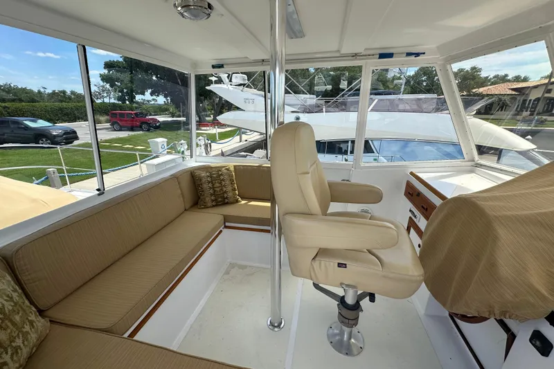 Slide: The Image of 1987 Kadey-Krogen Manatee 36 interior with beige seating and helm chair, docked outdoors. - 75