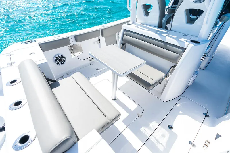 Slide: The Image of Manufacturer Provided Image: 2025 Sportsman Open 302 Center Console boat interior with seating and table on clear water. - 10