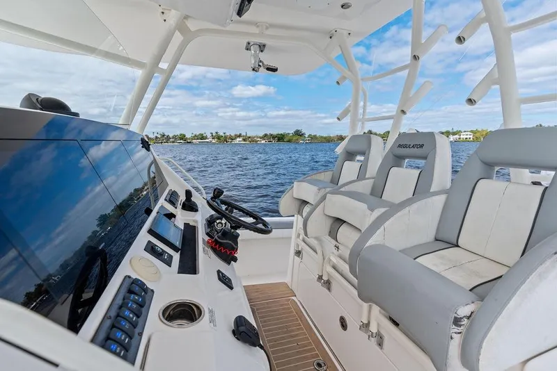 Slide: The Image of 2018 Regulator 41 boat cockpit with modern controls and seating, overlooking calm waters. - 23