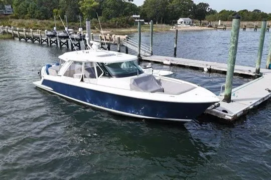 Slide: The Image of 2021 Tiara Sport 43 LS boat docked at a marina, featuring sleek design and blue hull. - 2