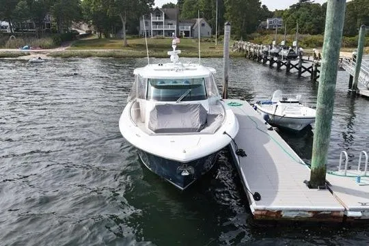Slide: The Image of 2021 Tiara Sport 43 LS luxury boat docked at marina with scenic background. - 3