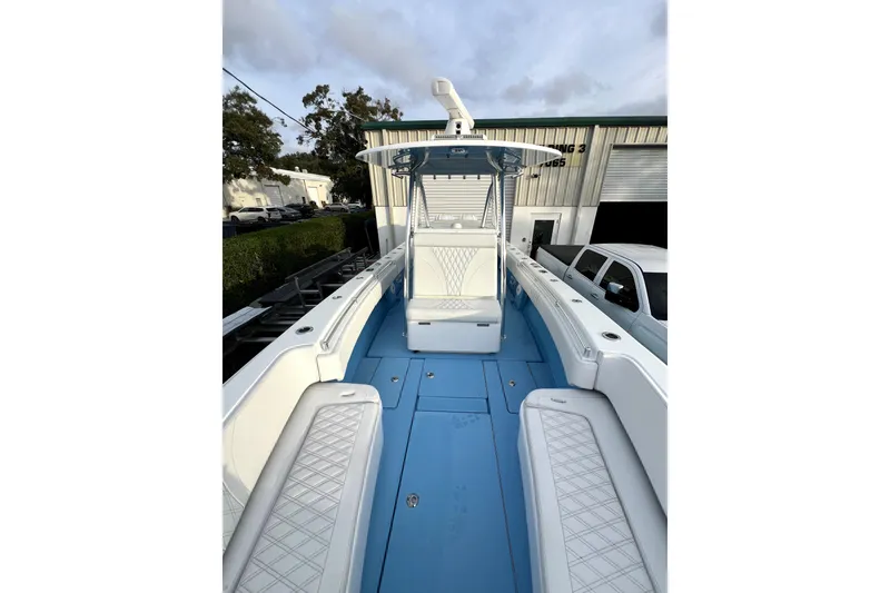 Slide: The Image of 2023 Contender 30 ST boat with blue deck and white seating, docked outdoors. - 12