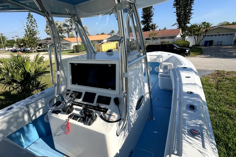 Slide: The Image of 2023 Contender 30 ST boat with modern helm, steering wheel, and blue deck in residential area. - 17